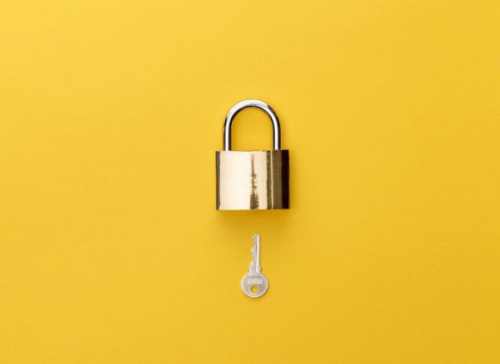 Overhead view of padlock and key on yellow background.