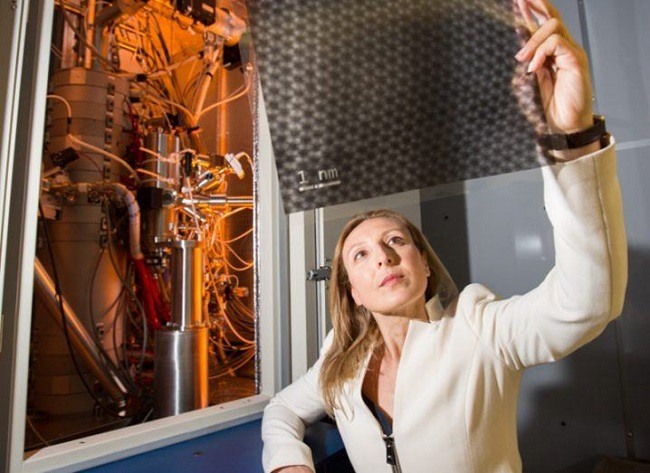 Valeria Nicolosi in a white blazer holding a sheet of nanomaterial up to the ligt in her lab.