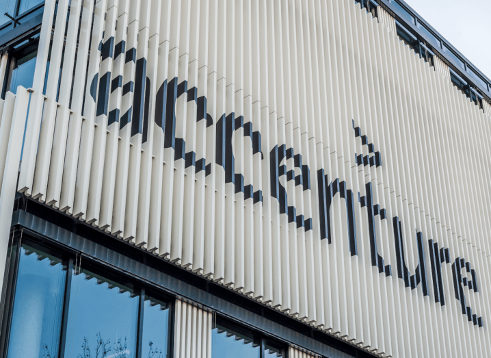 The Accenture logo in black on a white panelled background, on the exterior of a building.