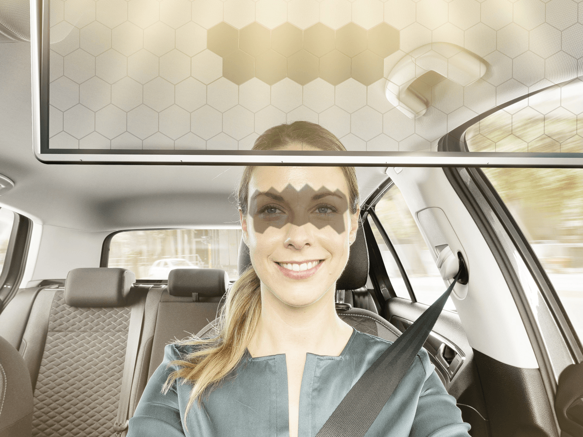 A woman driving in a car with a shadow on her eyes, which has been projected by a visor.