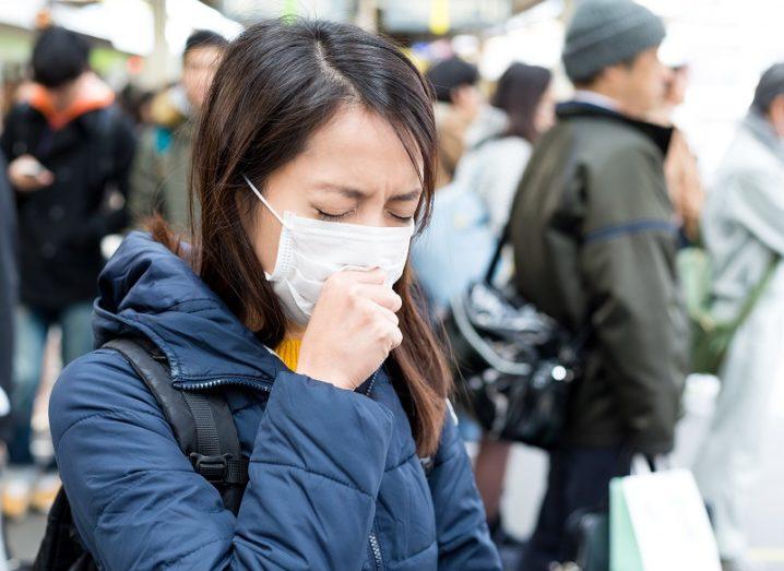 Woman wearing surgical mask on a busy street.