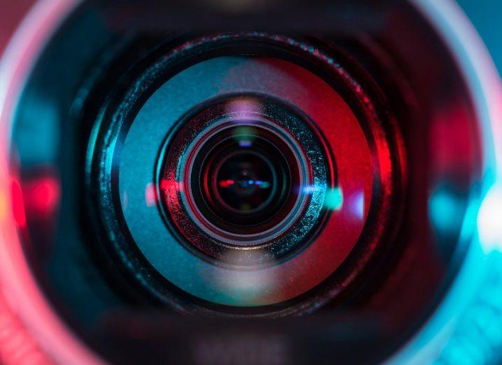 Close-up of a camera lens shrouded in red and blue light.