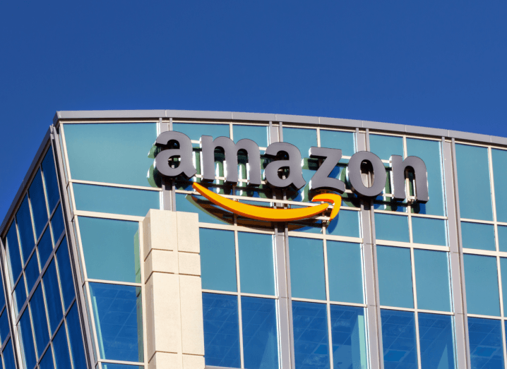 The Amazon logo on the facade of a building under a blue sky.