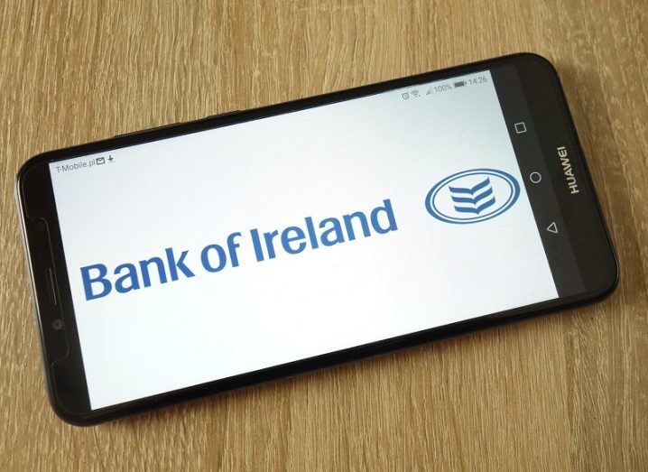 Phone on a wooden table with the Bank of Ireland logo on the screen.