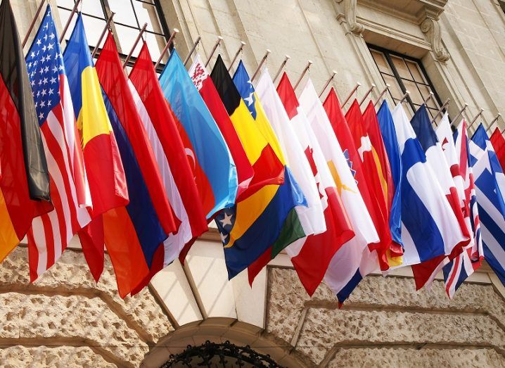 Flags of OECD members in a row outside a beige-brick building.