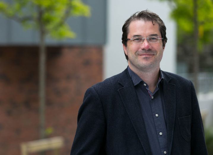 Alan Costello pictured outside a red-brick building with some saplings dotted in the background.