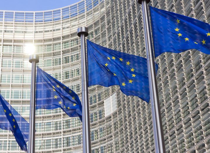 A row of European Union flags outside the European Commission building in Brussels on a sunny day.