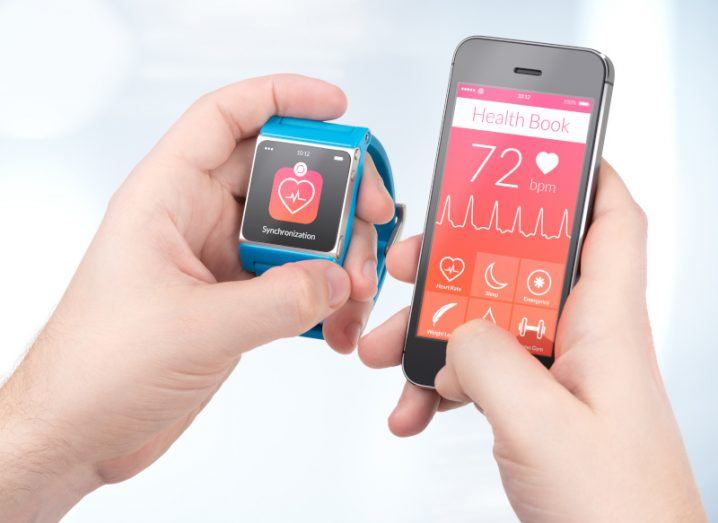 Someone holding a mobile and smart watch, showing various health stats.