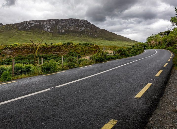 Empty road turning a bend in the Irish countryside.