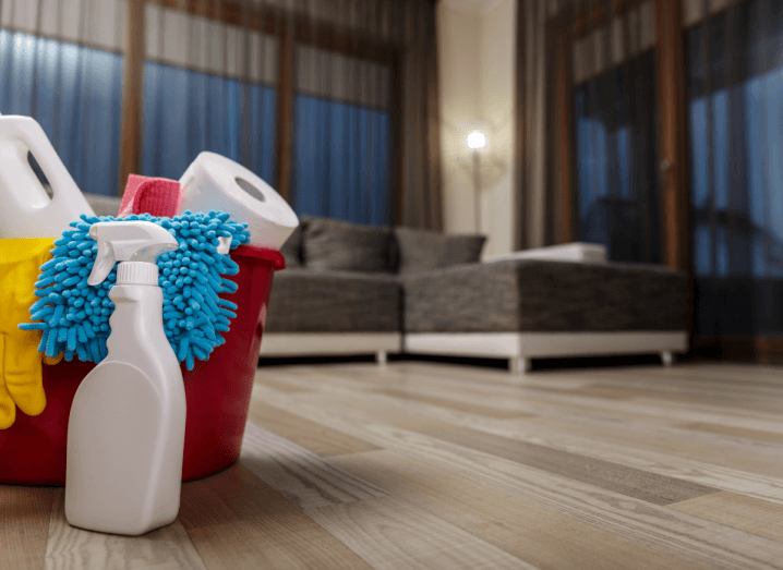 Cleaning equipment in a red bucket on the floor of a modern apartment.