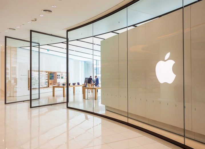 An Apple store with large windows and the Apple logo on a wall.