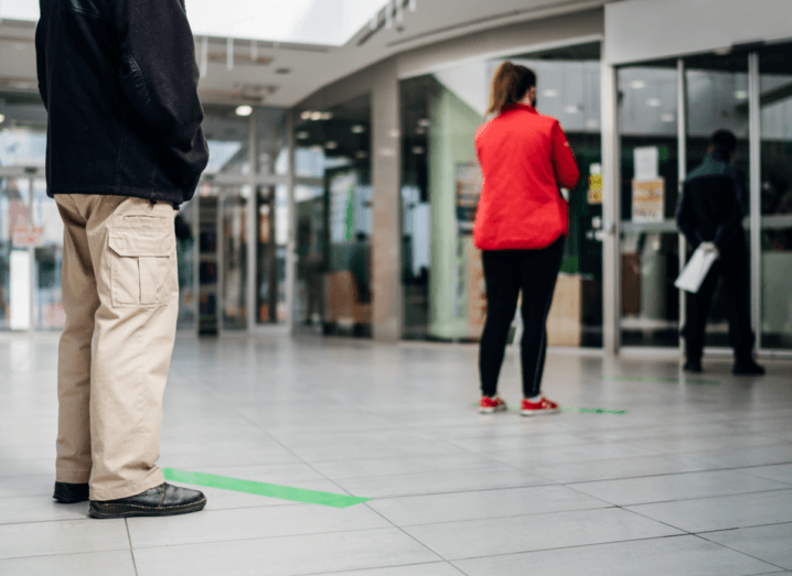 A queue of customers physical-distancing outside of a shop, with lines marked on the floor to show them how far to stand apart.