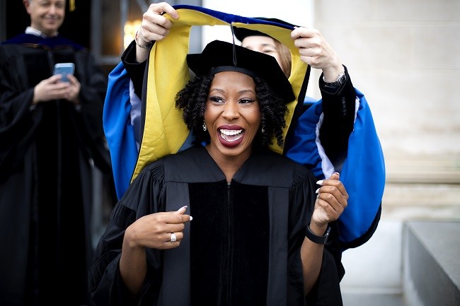 Ciara Sivels smiling while having her PhD graduation stole put on her. 