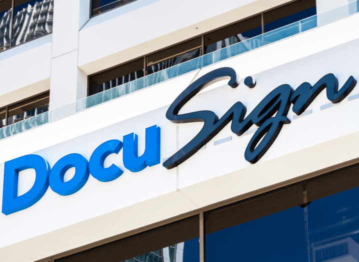 The DocuSign logo on the front of a building. There are windows above and below the logo, which is printed in blue and navy.