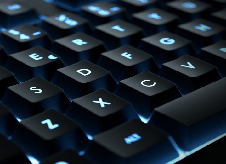 A close-up of a computer keyboard, with bright blue backlighting.