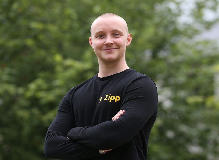 Zipp Mobility founder, Charlie Gleeson crossing his arms and smiling while standing against a leafy background.