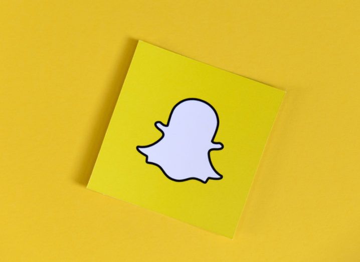 Snapchat logo on a yellow post-it note against a yellow background.