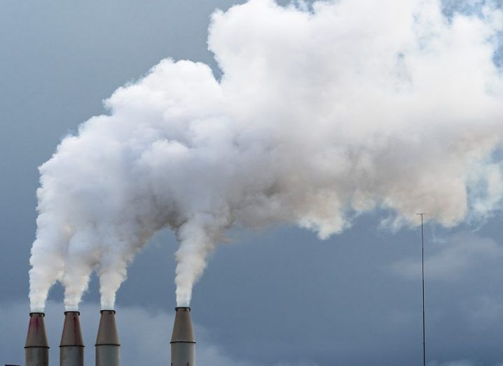 Smoke rising from four chimneys against a dark, cloudy sky.