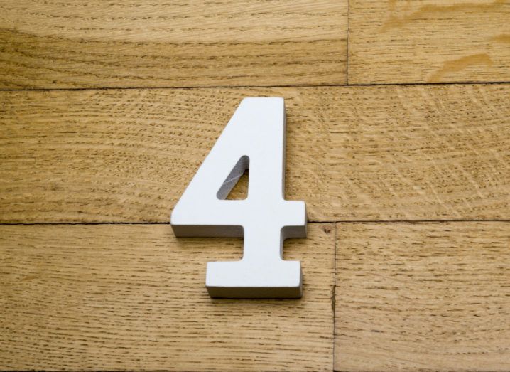 A white 3D number four on a wooden parquet floor.