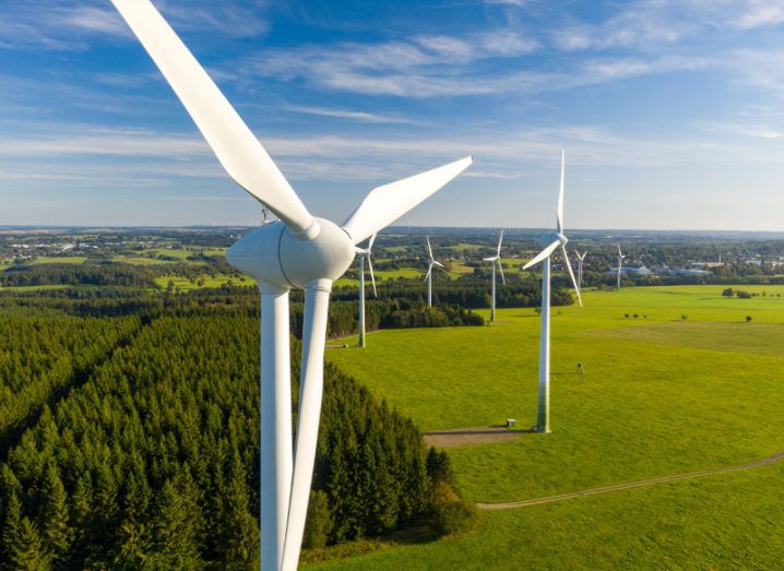 Photo of windfarms in green countryside against a blue sky.