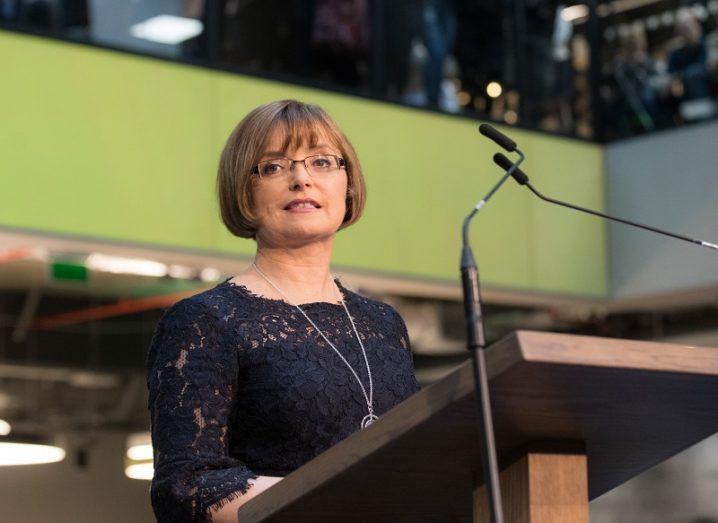 Cathriona Hallahan speaking at a podium against a green background.