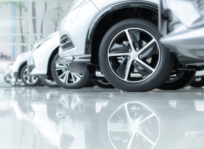 A fleet of silver cars reflecting off a white floor.