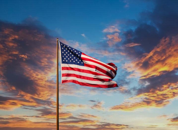 US flag blowing in the wind against a colourful sky at sunset.