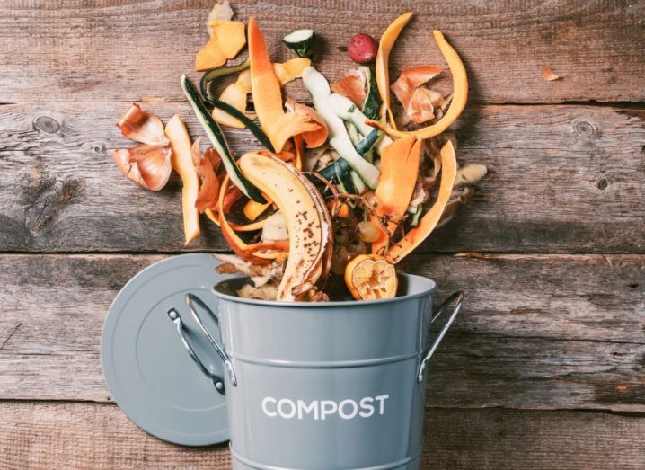 A bucket of food and household waste spilling over onto a wooden floor.