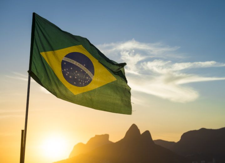 Brazilian flag backlit by a sunset at Ipanema Beach in Rio de Janeiro, Brazil.