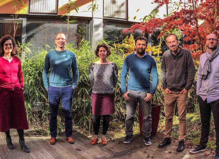 The Grapheal team. Six people stand in a line in smart-casual clothes on wooden decking in front of shrubbery.