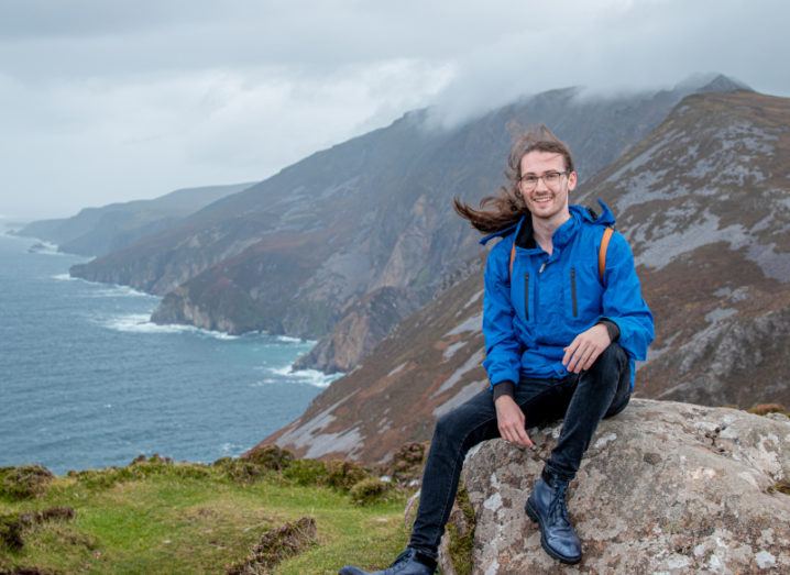 PhD researcher Lorin Sweeney poses by a cliff-edge overlooking the sea.