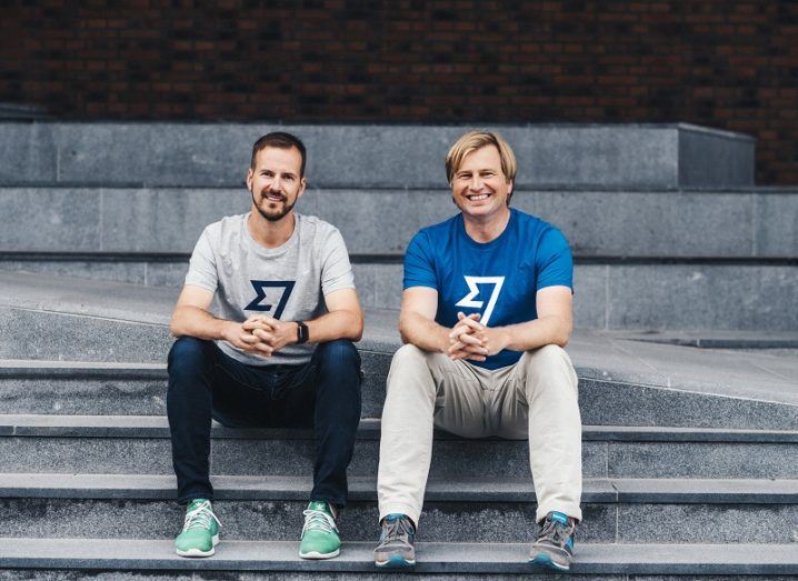 The two founders of TransferWise are sitting on a step, wearing T-shirts that feature the company's logo.