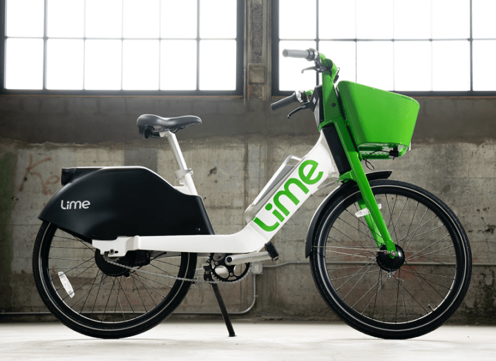 A white and green Lime-branded e-bike is standing in a warehouse.