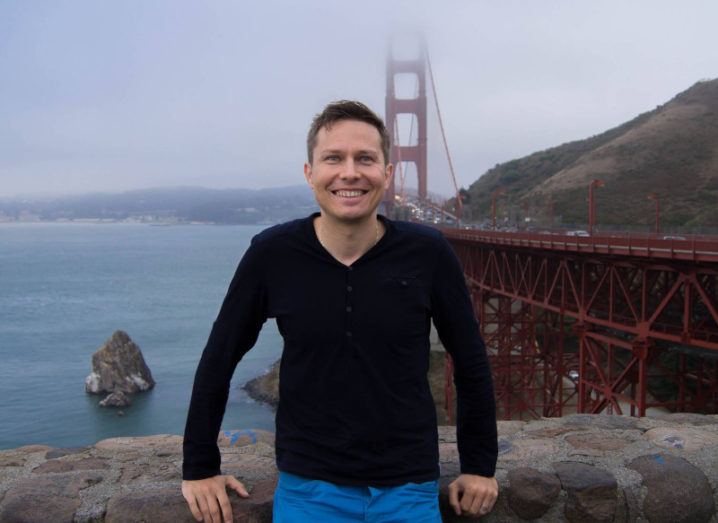 Dr Lukasz Porwol leans against a wall overlooking the Golden Gate Bridge in San Francisco on a misty day.