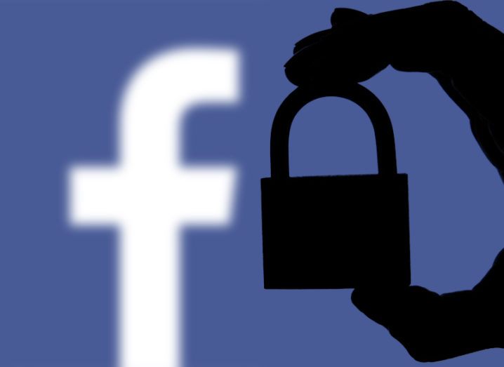 The Facebook logo is behind a silhouette of a hand holding a padlock.