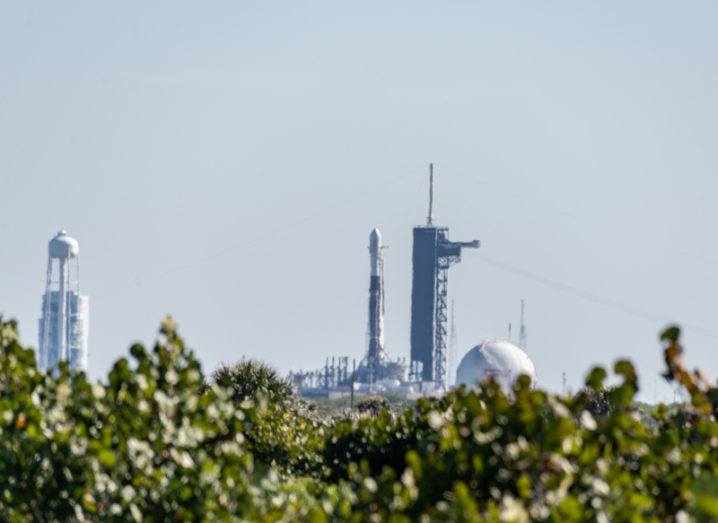 SpaceX Falcon 9 Starlink L-17 sitting on launch pad at Kennedy Space Center over a row of hedges on a bright day.