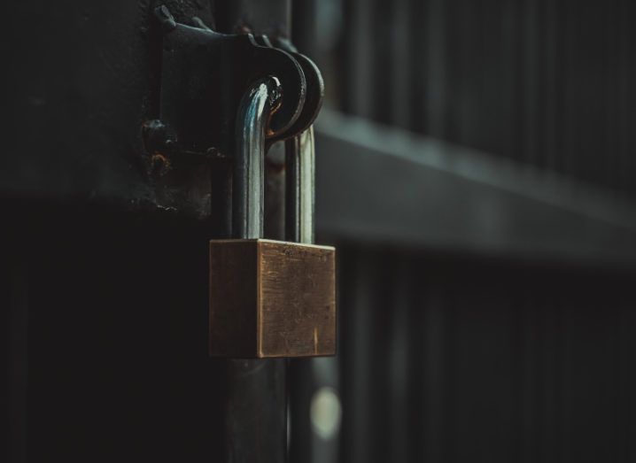 A gold padlock on a dark metal gate, symbolising data protection.