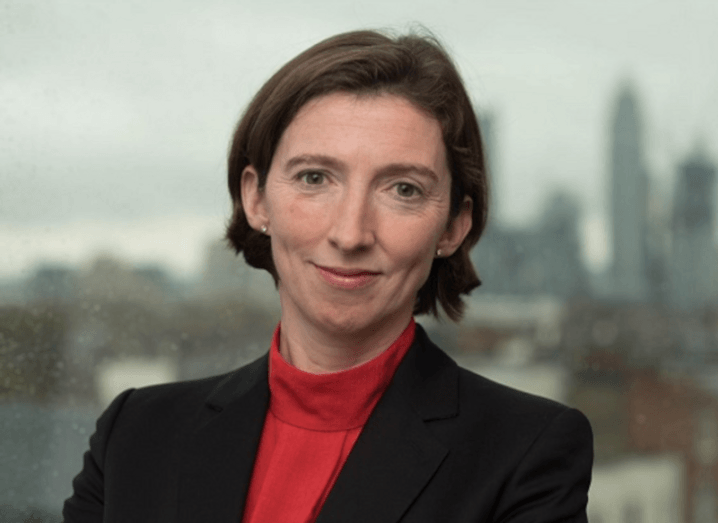 UK NCSC CEO Lindy Cameron poses in front of a window looking out on a dreary cityscape.