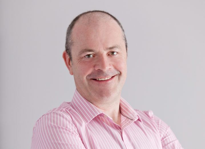 A headshot of Paul Meehan of HPE in a pink shirt, smiling at the camera against a grey background.