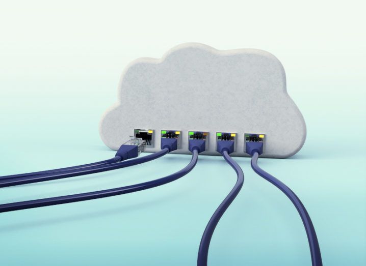 A cloud-native architecture concept. Several wires are plugged into the bottom of a 3D white cloud on a turquoise surface.