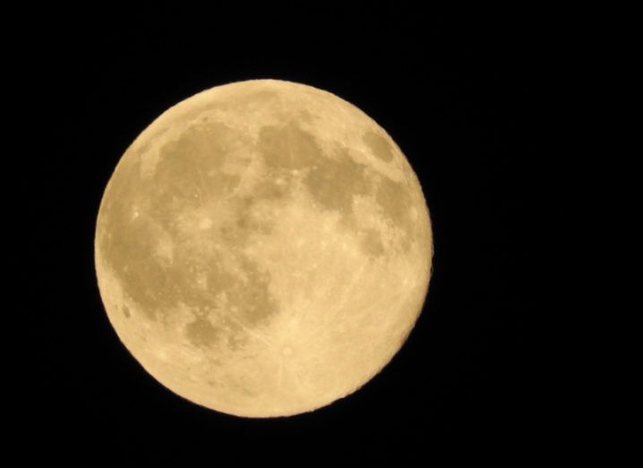 A picture of the yellow-tinted full moon in the night sky.