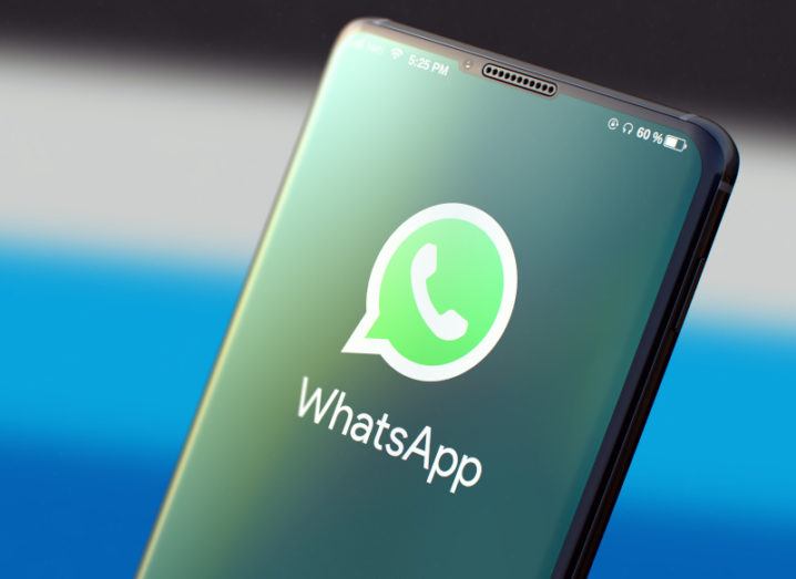 Close-up of a smartphone screen displaying the WhatsApp logo, a bright green speech bubble containing a telephone handset icon.