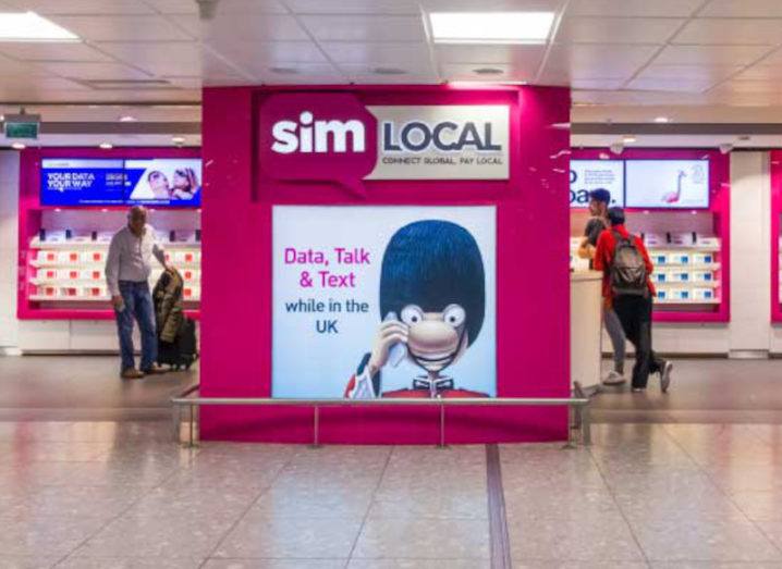 Travellers in an airport browse a Sim Local store, looking for local SIMs to avoid roaming charges.