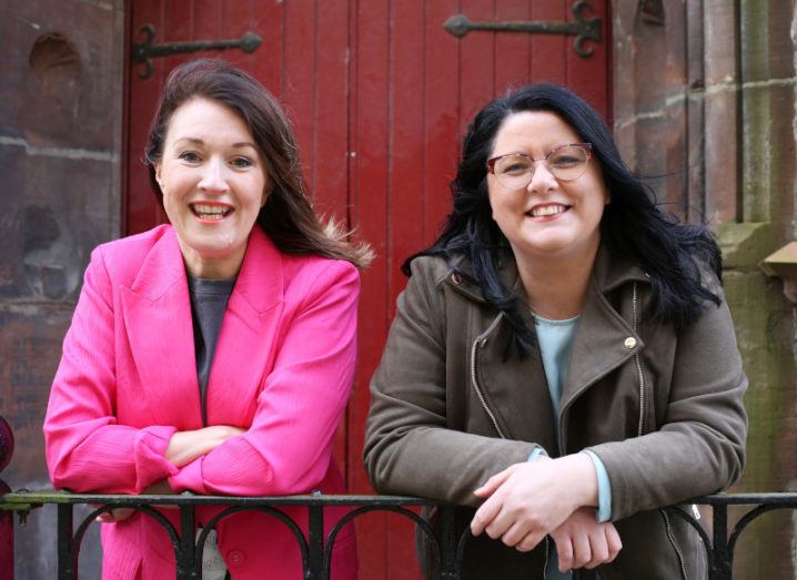 Jennifer Neff and Leann Monk-Özgül, founders of Elemental Software, pictured side by side, smiling and leaning on some railings outside a building.