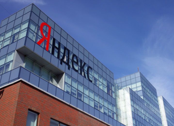 A Yandex office building is pictured from the street. The Yandex branding is visible on the side of the building.