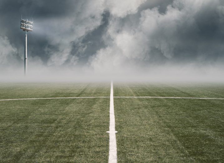 Empty football pitch shrouded in fog and clouds.