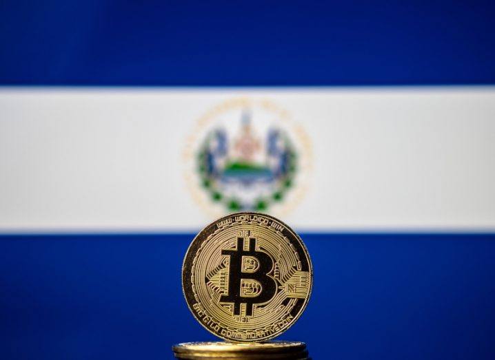 Image of a physical bitcoin in the backdrop of the El Salvador blue-and-white flag.