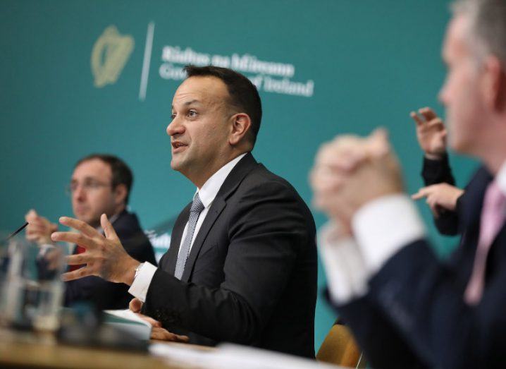 Leo Varadkar sits among a row of Government ministers at a long table, gesturing as he speaks to the press.