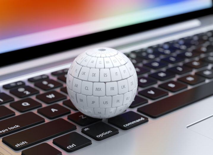 A spherical keyboard with different languages written on each key, placed over a normal laptop keyboard with multi-coloured laptop screen in the background.