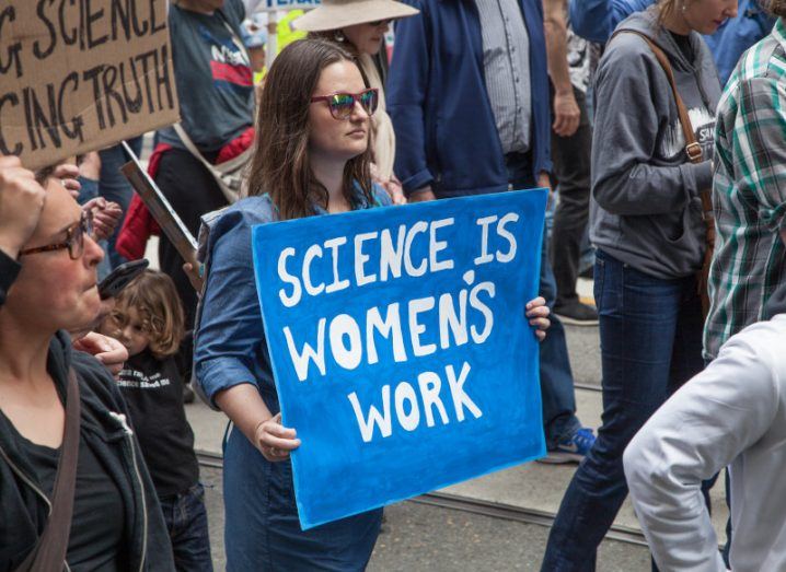 A woman marches in a crowd holding a sign that says: ‘Science is women’s work.’